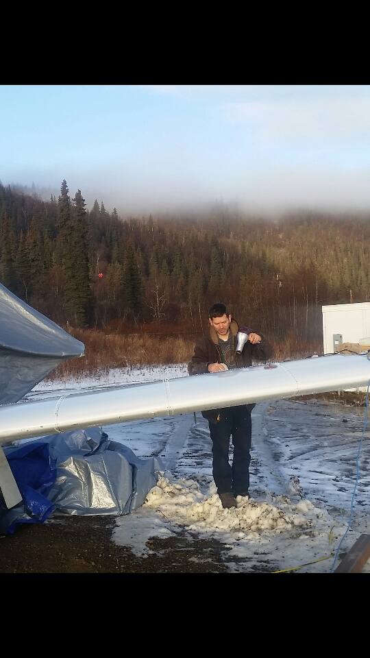 The next morning, we found the wind had blown so hard that the plane was not in quite the same position, and the tarps covering the wings were blown off. The light layer of ice was taken off with hair dryers.